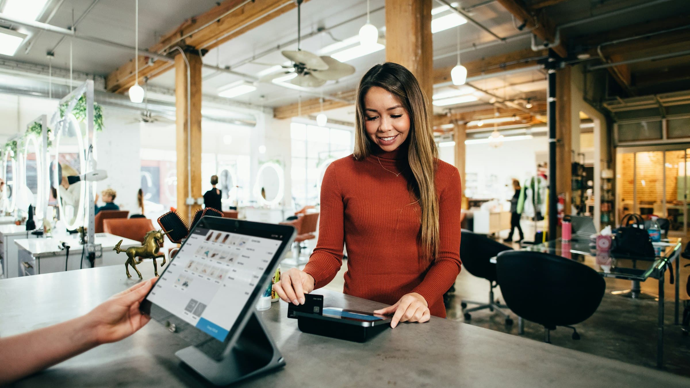 Guest paying at a counter tablet in a bright shop